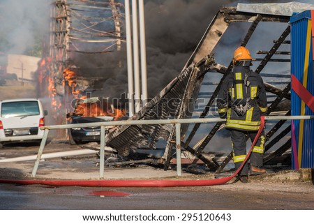 Fire fighter in the background of fire of buildings and cars. Firefighter in the foreground.