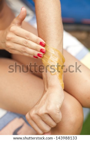 Female removing the strip of wax from arms - close-up shot