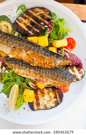 grilled mackerel with roasted vegetables served on plate in restaurant