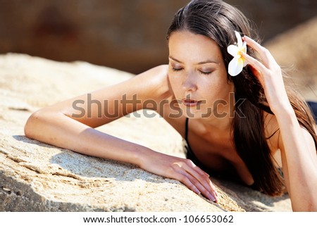 Closeup portrait of beautiful young woman with golden tan resting at beach in summer