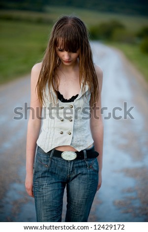 Young lonely woman with wet hair staying on road dropping down her head