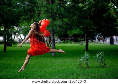 Beautiful woman in red jumping in park