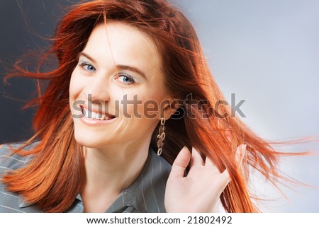 Beautiful redheaded business woman on gray studio background