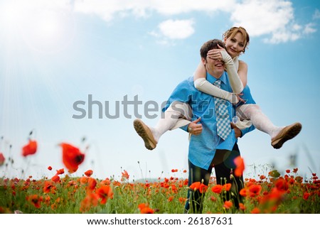 Wedding couple playing at poppy field outdoors on blue sky background