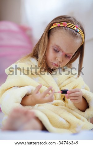 Little girl playing with cosmetics of her mother at home