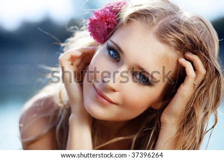 Portrait of young beautiful smiling female with flowers in her wet hair