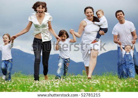 Group of happy parents with children running in field