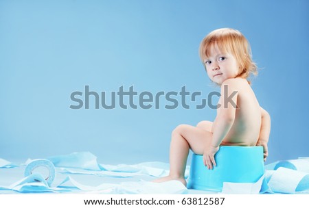 Studio shot of funny toddler sitting on potty chair and playing with toilet paper