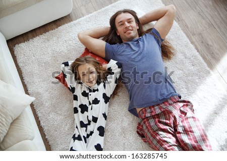 Portrait of child with father wearing pajamas lying down on a carpet
