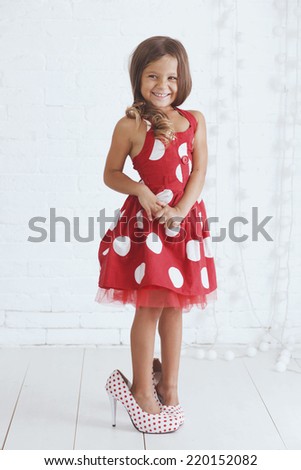 5 years old kid girl wearing stylish retro dress and heels posing over white background
