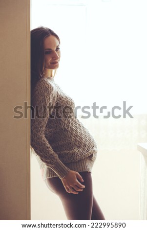 Home cozy portrait of pregnant woman wearing warm cashmere sweater resting at home