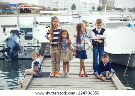 Group of 6 fashion kids wearing same navy clothes in marine style walking in the sea port
