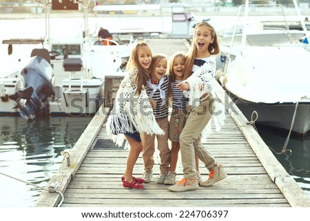 Group of fashion kids wearing navy clothes in marine style having fun in the sea port