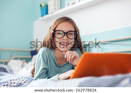 8 years old child having fun using laptop at her bedroom