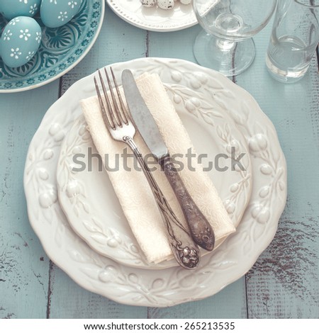Easter table setting with holiday decor on mint wooden background, top view point