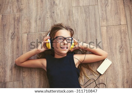 9 years old child is lying down on the floor and listening to music, top view point