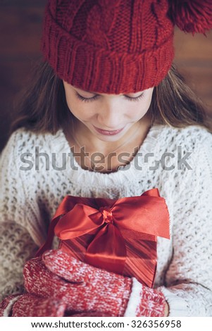Child giving a Christmas present on rustic wooden background, farmhouse interior.