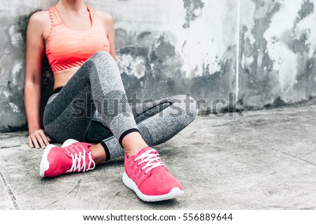 Fitness sport woman in fashion sportswear doing yoga fitness exercise in the city street over gray concrete background. Outdoor sports clothing and shoes, urban style. Sneakers closeup. Foto stock © 