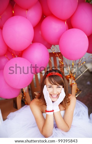 Cheerful bride of 60s style posing with bunch of balloons