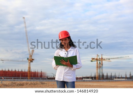 Young Female construction engineer / architect with a workbook and working at a construction site