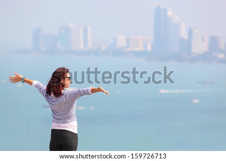 Happy celebrating winning success woman at sunset or sunrise standing elated with arms raised up above her head