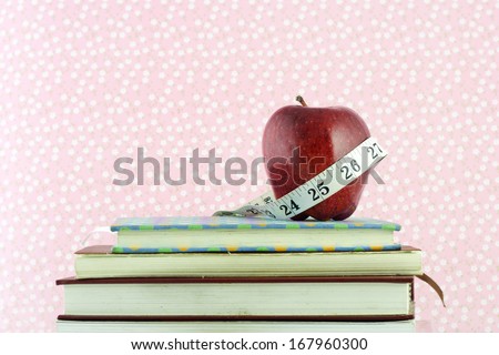 A red shiny apple, wrapped with a white measuring tape to signify dieting and weight loss.