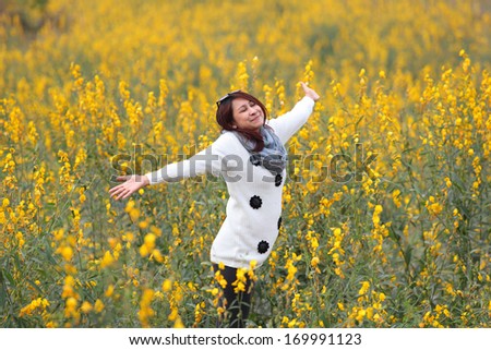 woman happy in free freedom pose with arms raised up towards the sky with smiling cheerful, elated expression of happiness. Beautiful girl in colorful of yellow blossom ,  flower forest outdoor