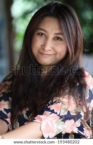 Relaxing woman sitting comfortable in sofa lounge chair smiling happy looking at camera. Resting beautiful young multicultural asian caucasian girl in her 40s