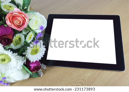Tablet computer and beautiful bouquet of flowers on wood table