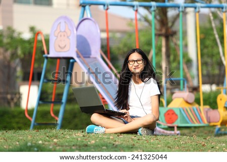 note book computer. Relaxed young teenage in garden smiling content, happy and reading on tablet pc at home in garden. Lifestyle image of beautiful mixed Asian Caucasian girl relaxing smiling happy