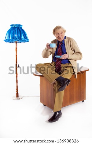 An elderly man on the Internet related to electronic tablet and drinking tea
