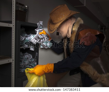 A thief wearing a mask steals money from the safe