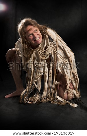 man with long hair in the ancient character stretches his hand to the camera on a black background