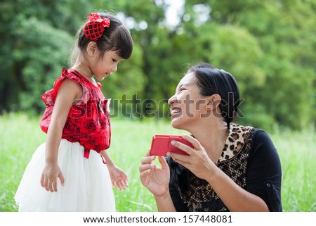 Mother teaching her daughter to play mobile phone