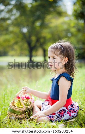 Little European girl holding basket of flower