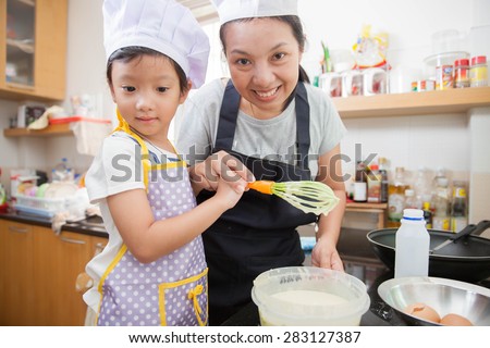 Asian mother teaching daughter making pancake