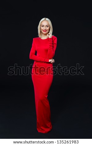 Smiling pretty woman in a red dress on a black background