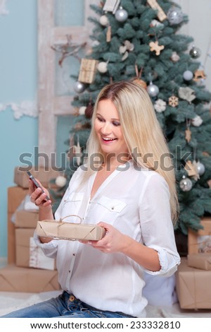 Beautiful smiling young woman with gift box in hands.Phone