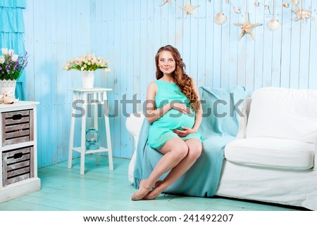 young beautiful pregnant woman in a dress in a marine interior