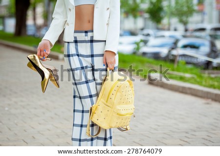 Detail of a beautiful young woman in pants and high-heeled shoes posing in the city streets . Fashion .