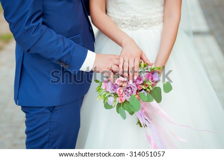 Beautiful wedding bouquet in hands of the bride and groom. Wedding rings.