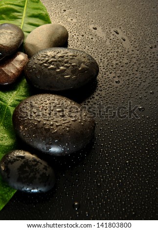 wet massage stones with green leaf and water drops