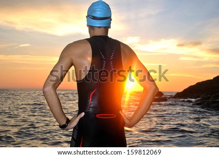 young athlete triathlon in front of a sunrise over the sea