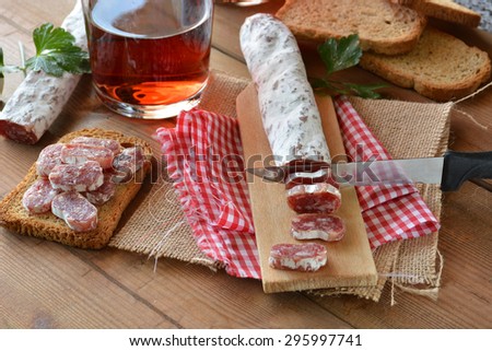 Spanish fuet salami on a cutting board with a glass of wine