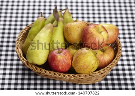 A basket of apples and pears on black-white checkered tablecloth.