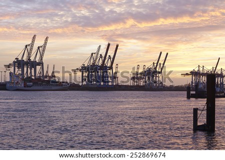 HAMBURG, GERMANY - FEBRUARY, 8. The Port of Hamburg (Germany) with container gantry cranes as silhouettes against a glowing orange yellow sky (sunset glow) taken on February 8, 2015.