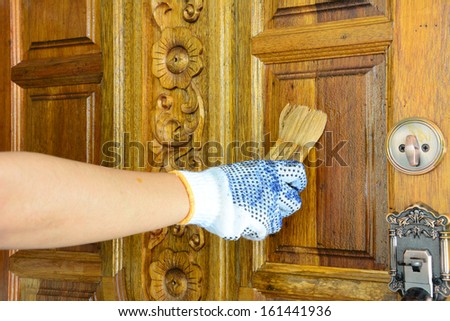 Hand with paintbrush painting a door Teak.