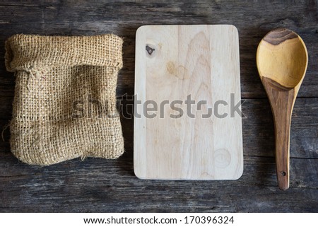 empty wooden board, ladle and sack on a table.