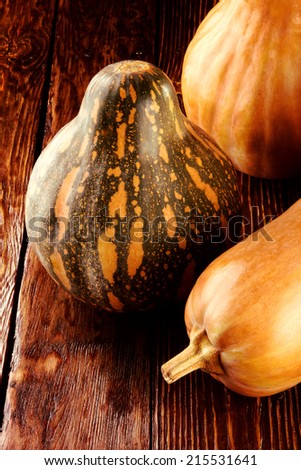 three different kinds of pumpkins lay on a wooden board