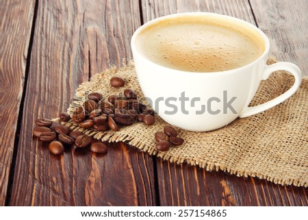 white cup brewed coffee costs on sacking on wooden table background